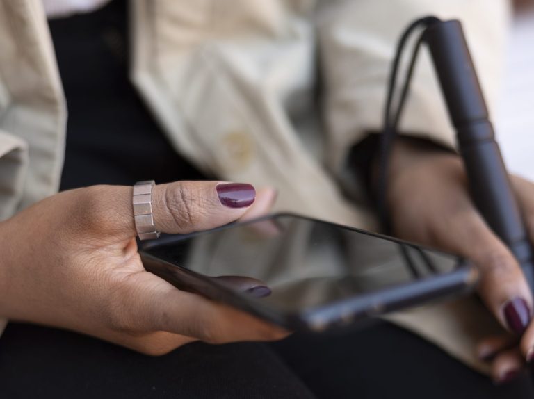 high-angle-hands-holding-smartphone-cane
